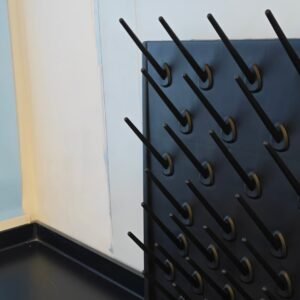 Wall-mounted glassware drying rack with angled black pegs and drain tray